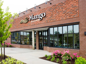 grandopening-mango-16-2-1 The exterior of Mango Salon, a brick building with large windows and landscaped flowers in front. - Mango Salon, VA