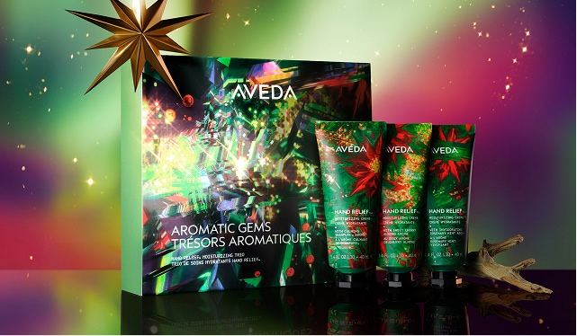 Aveda Aromatic Gems gift set with three hand relief creams in a colorful box, featured at Mango Salon—perfect for beauty lovers this holiday season. Displayed next to a golden star and festive branch on a multicolored background. - Mango Salon, VA