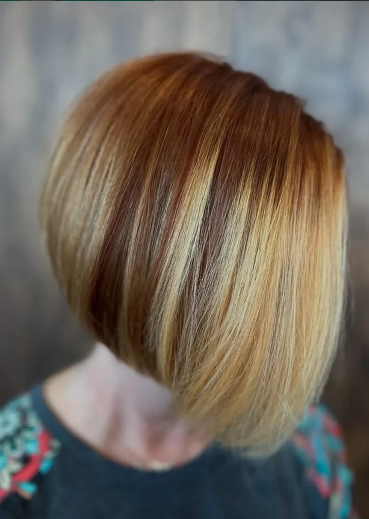 Person with a short, angled bob haircut featuring a blend of light blonde and brown colors, facing downward with hair covering the face. - Mango Salon, VA