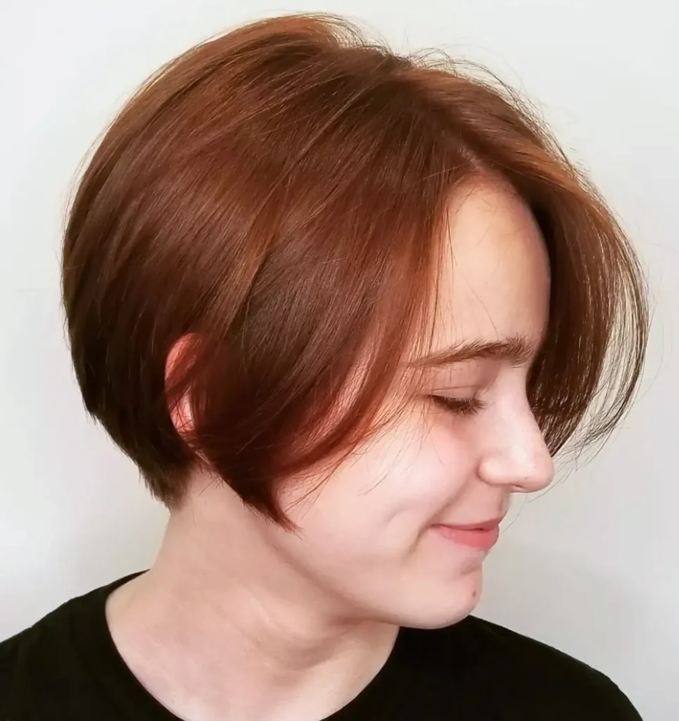 Person with short, straight, light brown hair, shown in profile with eyes closed and a slight smile, wearing a black shirt against a plain light background. - Mango Salon, VA