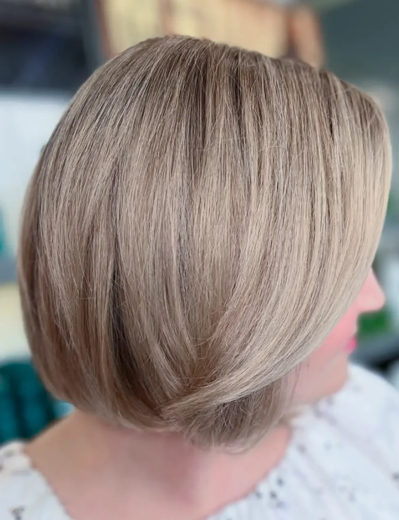 Person with straight, light brown hair in a chin-length bob hairstyle, viewed from the side, wearing a white patterned top. - Mango Salon, VA